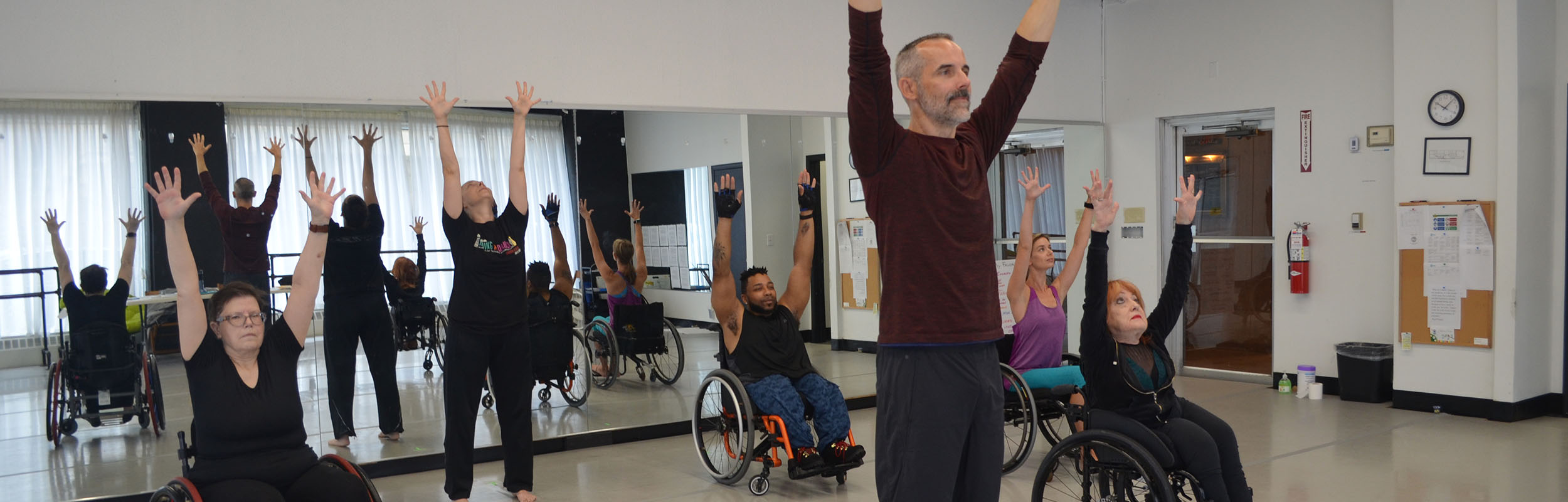 Stand-up and sit-down dancers reach their arms overhead in a Level 1 Teacher Certification class