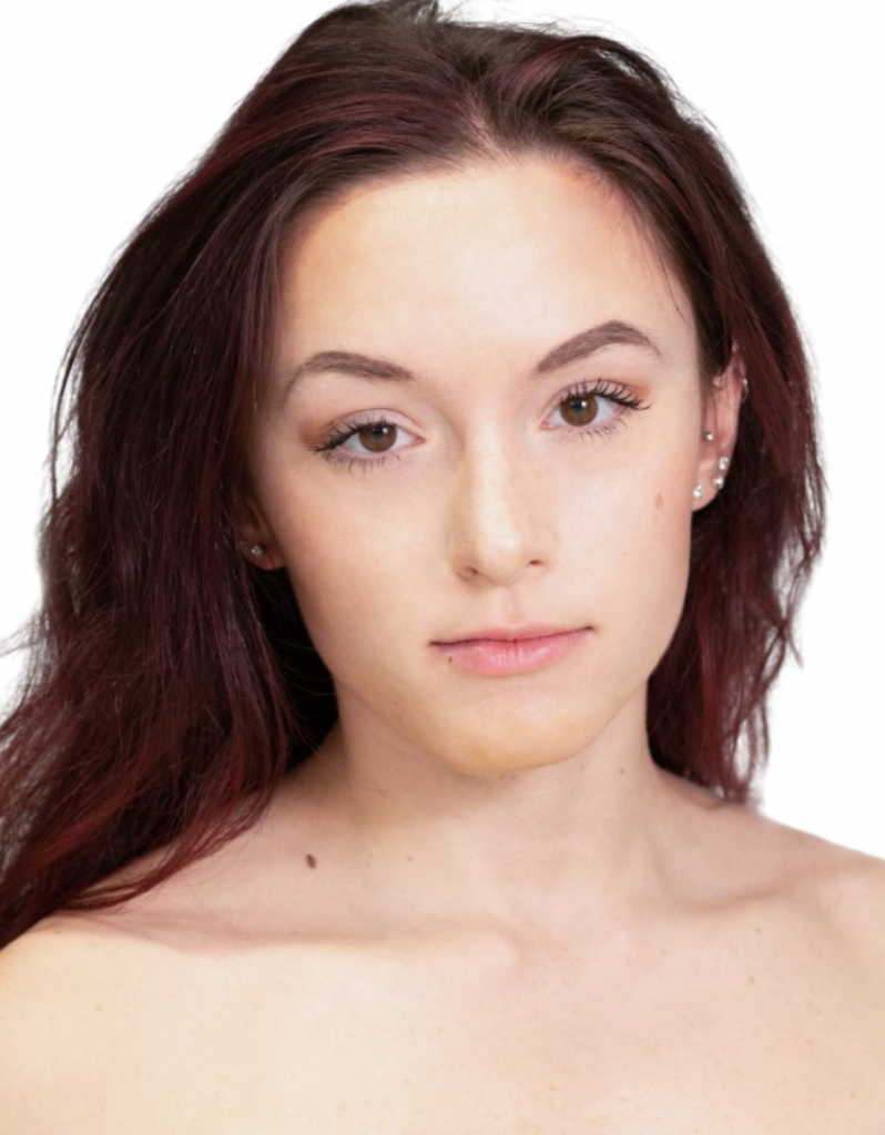Angelina DiFranco headshot looking at the camera with a slight smile, closed lips, bare shoulders, fair skin, long curly red brown hair.