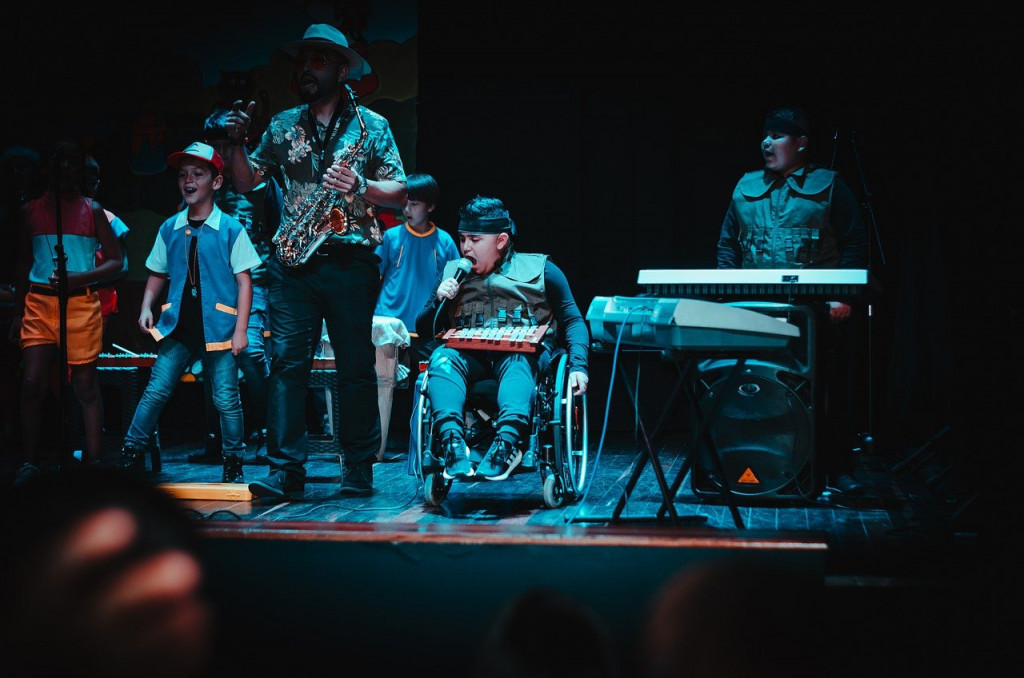 A group of musicians, one a wheelchair user, performing on stage.