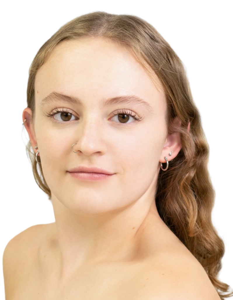 Kylie Karam headshot looking at the camera with fare skin, bare shoulders, gentle smile, light curly hair worn parted and down past shoulders.