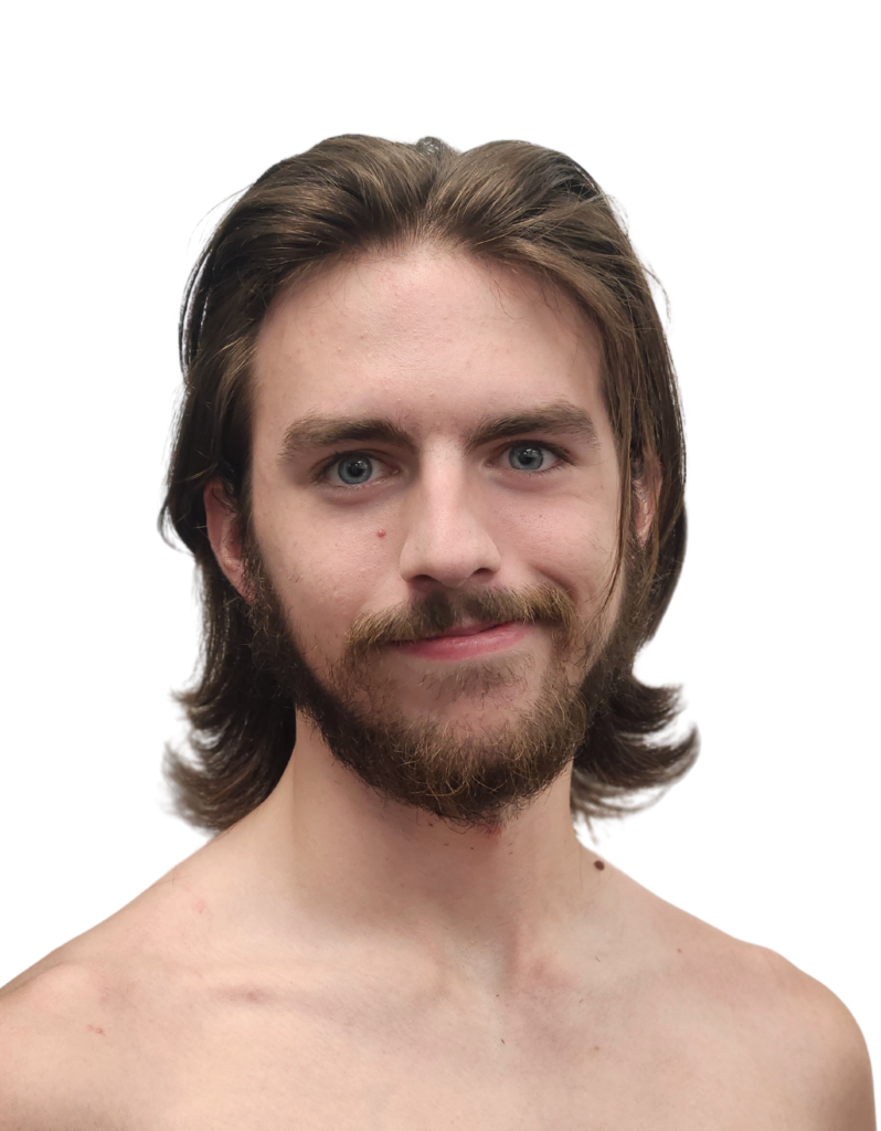 Zach Biggs headshot fare skin, bare shoulders, gentle smile, facial hair over lip and on chin, medium length brown hair.